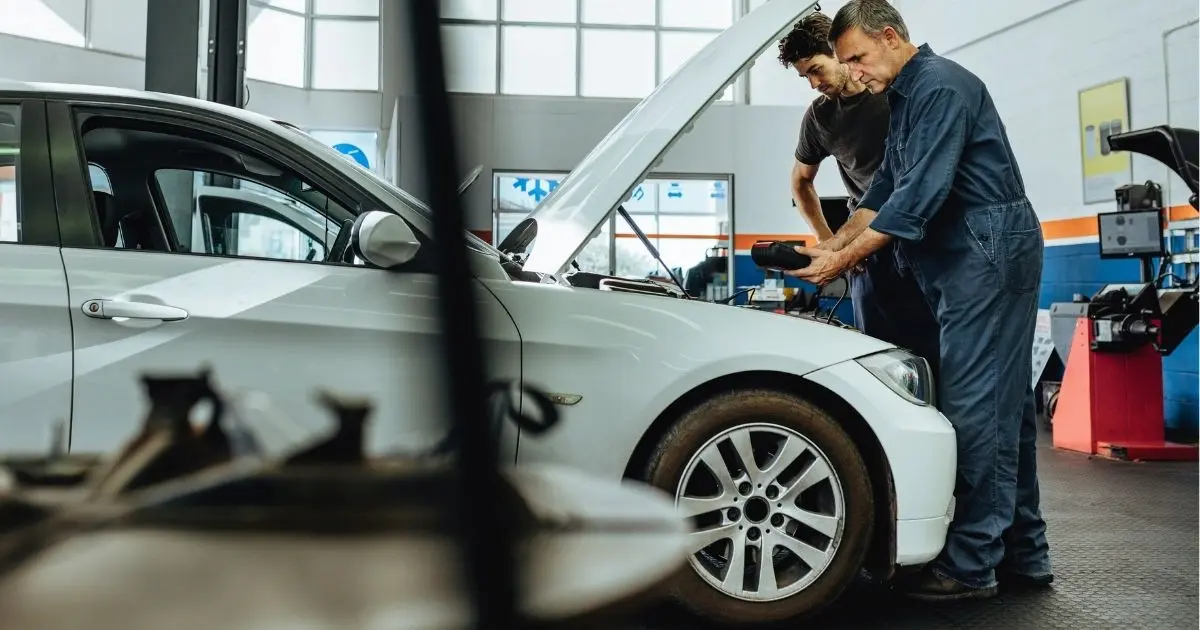 Used car buyer asking questions while a mechanic inspects the vehicle