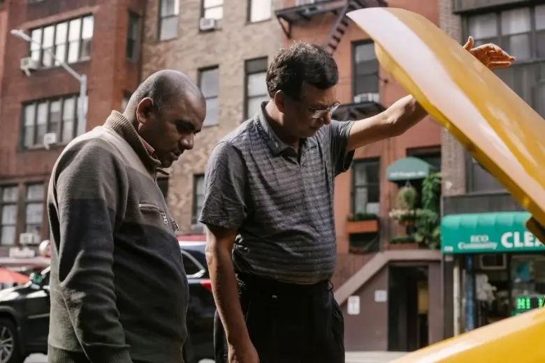 Used car buyer asking the seller questions while checking under the hood