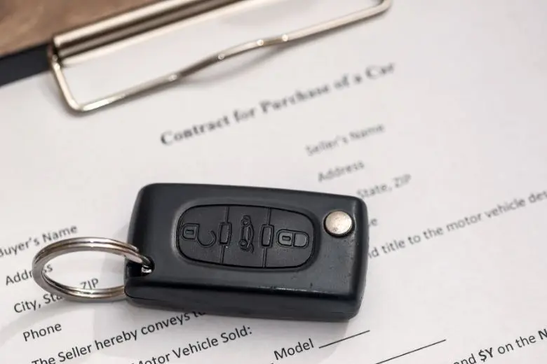 Used car title paperwork and keys being checked before the sale