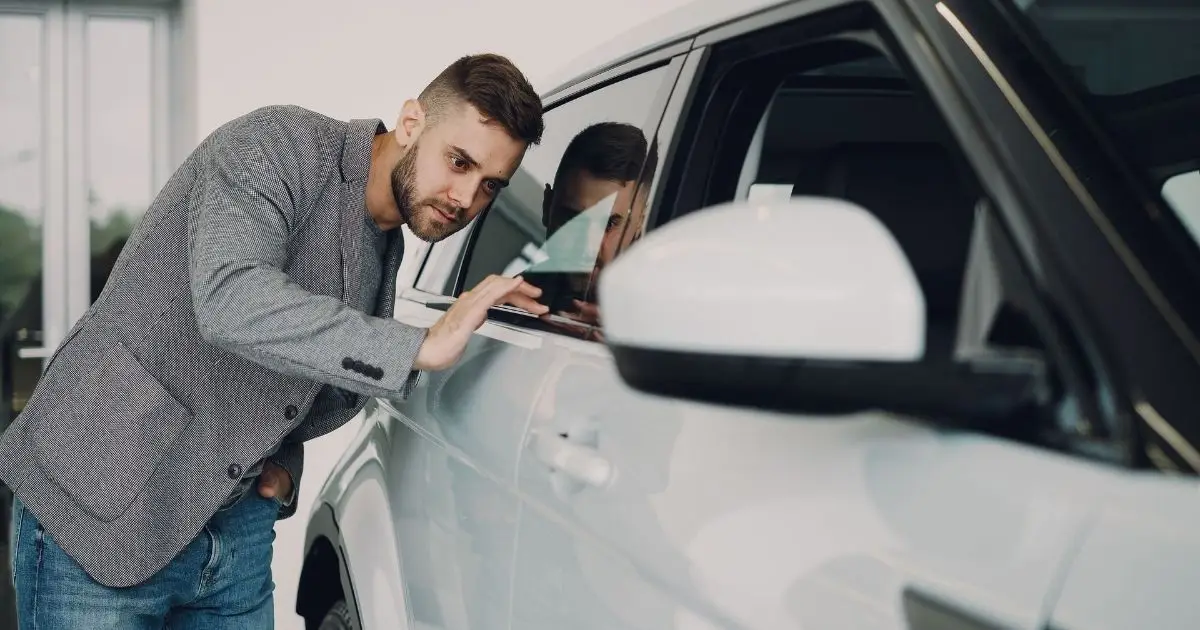 Man inspecting a car at a dealership before buying