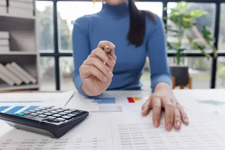 Person using a calculator with financial paperwork to compare total contract costs