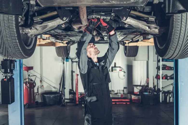 Mechanic inspecting the underside of a car raised on a repair shop lift